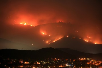 A mountain on fire at night, with a city in the valley.